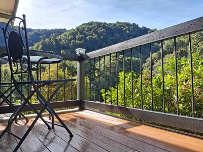 a chair on a balcony with a view of the mountains at Cabaña Tangara in San Gerardo de Dota