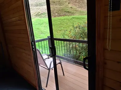 a chair sitting on a porch looking out the door at Cabaña Tangara in San Gerardo de Dota