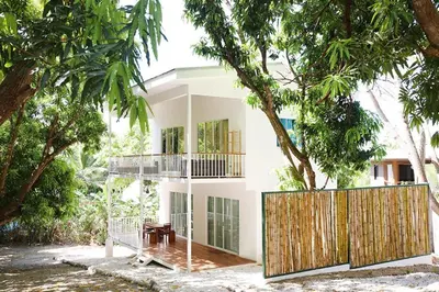 a white house with a wooden fence and trees at Kai Villa in Santa Teresa Beach