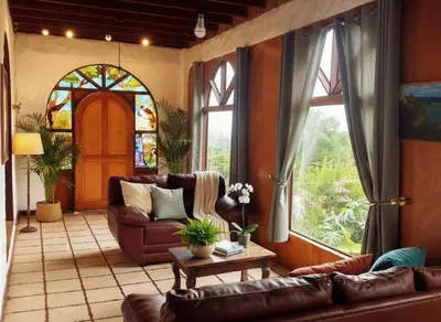 a living room with leather furniture and a stained glass window at Rainbow House in Monteverde Costa Rica