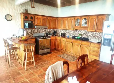 a kitchen with wooden cabinets and a table in it at Rainbow House in Monteverde Costa Rica