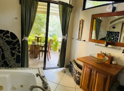 a bathroom with a tub and a view of a patio at Enchanted sonido de la selva in Quepos