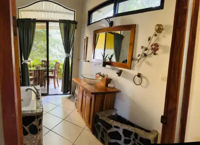 a bathroom with a sink and a mirror on the wall at Enchanted sonido de la selva in Quepos