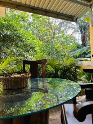 a glass table and a chair on a patio at Enchanted sonido de la selva in Quepos