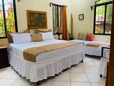 two beds in a room with windows at Enchanted sonido de la selva in Quepos