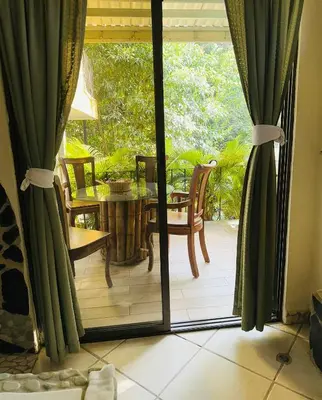an open door to a patio with a table and chairs at Enchanted sonido de la selva in Quepos