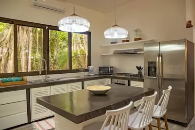 a kitchen with a counter with a refrigerator and chairs at Oceano 5 - Walk to the beach in Playa Pelada