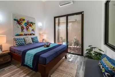 a bedroom with a bed with a blue comforter at Oceano 5 - Walk to the beach in Playa Pelada