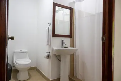 a bathroom with a toilet and a sink and a mirror at Fuego del Sol Beachfront Hotel in Jacó