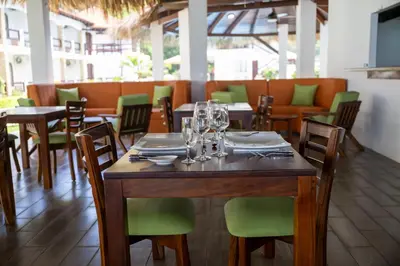 a dining room with wooden tables and green chairs at Fuego del Sol Beachfront Hotel in Jacó