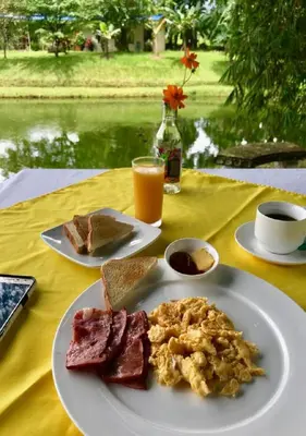 a table with a plate of breakfast food and a glass of orange juice at Hotel Colores del Arenal in Fortuna
