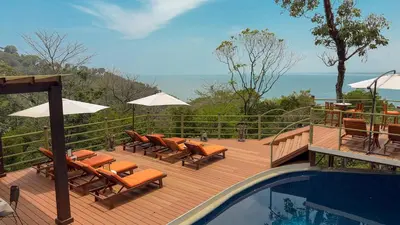 a wooden deck with chairs and a swimming pool at Issimo Suites (Adults Only) in Manuel Antonio