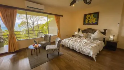 a bedroom with a bed and a large window at Issimo Suites (Adults Only) in Manuel Antonio
