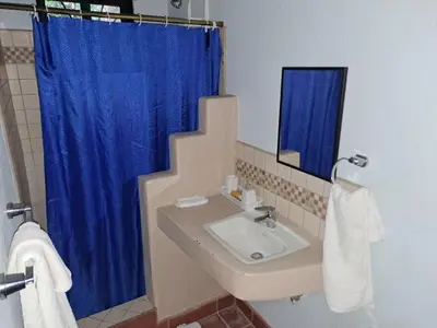 a bathroom with a sink and a blue shower curtain at Casa Rosada Nosara in Nosara