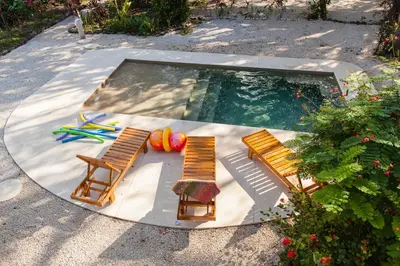 a swimming pool with two chairs and a table at Casa Rosada Nosara in Nosara