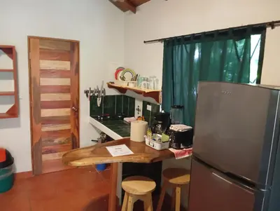 a kitchen with a wooden table and a refrigerator at Casa Rosada Nosara in Nosara