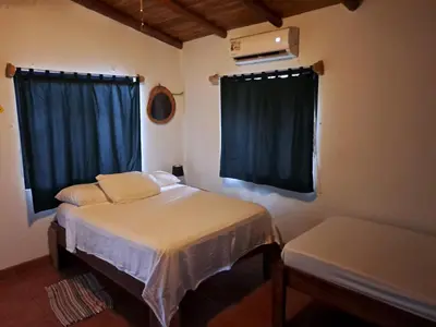 a small bedroom with two beds and a window at Casa Rosada Nosara in Nosara