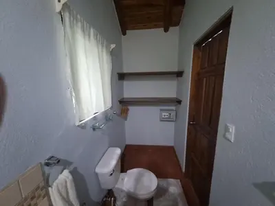 a small bathroom with a toilet and a window at Casa Rosada Nosara in Nosara