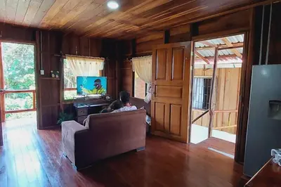 a couple sitting on a couch in a living room at Cabaña Finca el Corteza in Fortuna