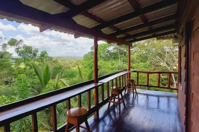 a balcony with chairs and a view of the forest at Cabaña Finca el Corteza in Fortuna