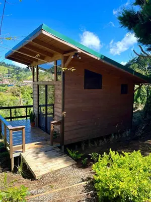 a small wooden cabin with a bench on a deck at Cypress House Costa Rica in San Cristóbal Norte