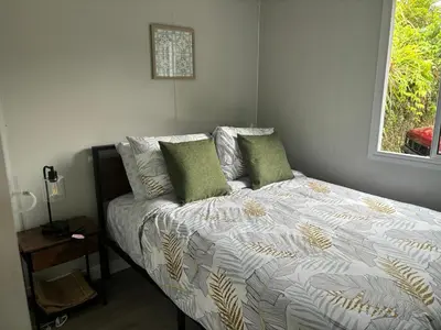 a bed with green pillows in a bedroom with a window at Gaspar Arenal Volcano in Fortuna
