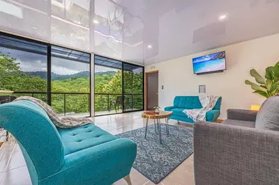 a living room with blue furniture and a large window at Z orro Tropical in Arbolito