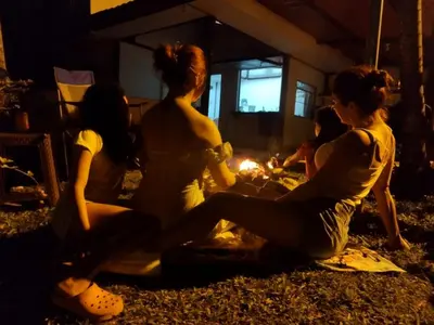 a group of women sitting around a fire in a room at Cabaña Dream House in Pejibaye