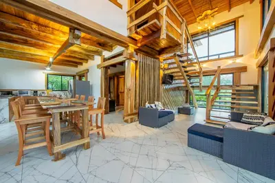 a living room with wooden ceilings and a spiral staircase at Two Volcanoes Villa Fortuna in Fortuna