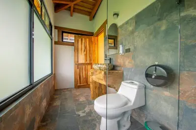 a bathroom with a toilet and a glass shower at Two Volcanoes Villa Fortuna in Fortuna