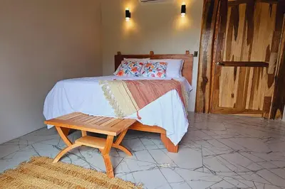 a bedroom with a bed with a bench next to it at Two Volcanoes Villa Fortuna in Fortuna