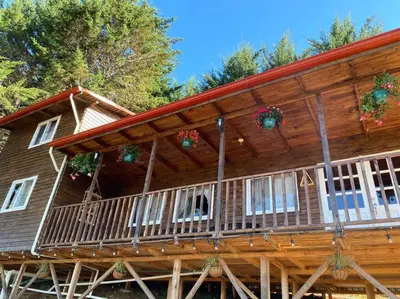 a log cabin with christmas decorations on the porch at Cabaña Aurora – COZY Cabin with an Amazing view! in San Pablo