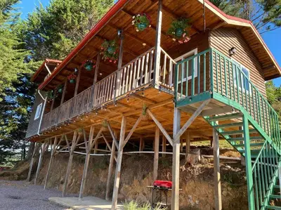 a large wooden house with a staircase on it at Cabaña Aurora – COZY Cabin with an Amazing view! in San Pablo