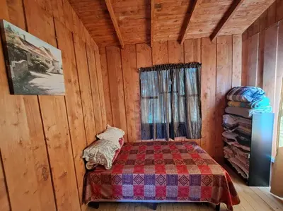 a bedroom with a bed in a wooden cabin at Cabaña Duende Oscuro - Paradise IN THE Mountains! in San Pablo