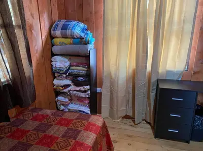 a room with a pile of folded clothes and a bed at Cabaña Duende Oscuro - Paradise IN THE Mountains! in San Pablo