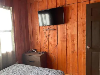 a bedroom with a television on a wooden wall at Cabaña Duende Oscuro - Paradise IN THE Mountains! in San Pablo