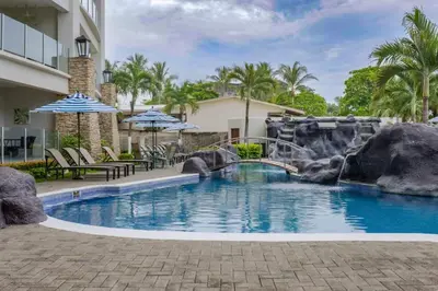 a swimming pool with a waterfall in a resort at Diamante del Sol 303S- 3rd Floor Ocean View in Jacó