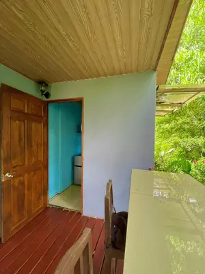 a room with a door and a table on a deck at Cabañas el Bosque del Arenal in Guayabal