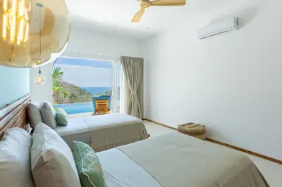 a bedroom with two beds and a view of the ocean at Stylish ocean view Villa Blume at Hermosa Hills in Playa hermosa