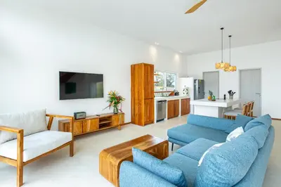 a living room with two blue couches and a kitchen at Stylish ocean view Villa Blume at Hermosa Hills in Playa hermosa