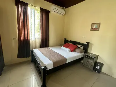 a bedroom with a bed with red pillows and a window at Beautiful View House in Tortuguero