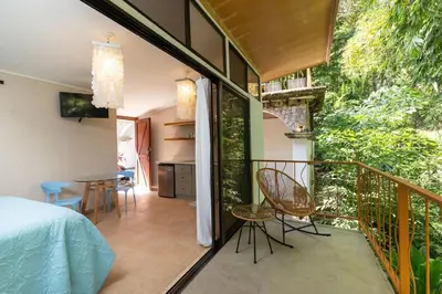 a bedroom and a balcony with a bed and a table at Restful Casa Quetzal Luxurious Rainforest Retreat in Quepos