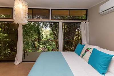 a bedroom with a bed and a large window at Restful Casa Quetzal Luxurious Rainforest Retreat in Quepos