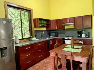 a kitchen with a wooden table and a stainless steel refrigerator at Cozy 2BR EcoCondo 3 w Free Security WiFi in Quepos