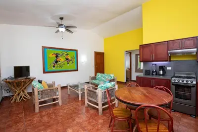 a living room with a table and a kitchen with yellow walls at Cozy 2BR EcoCondo 3 w Free Security WiFi in Quepos