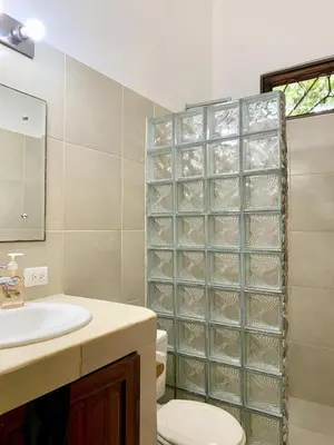 a bathroom with a sink and a toilet and a mirror at Cozy 2BR EcoCondo 3 w Free Security WiFi in Quepos