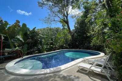 a swimming pool with two chairs and a table and a chair at Cozy 2BR EcoCondo 3 w Free Security WiFi in Quepos
