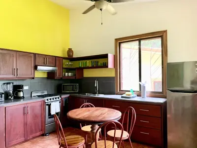 a kitchen with a wooden table and a table and chairs at Cozy AC EcoCondo 4 with Pool Wildlife Visits in Quepos