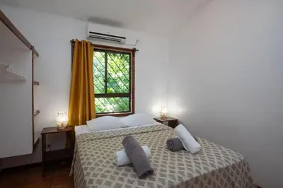 a bedroom with a bed with two pillows and a window at Cozy AC EcoCondo 4 with Pool Wildlife Visits in Quepos