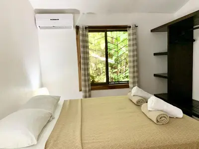 a bedroom with a bed with two towels on it at Cozy AC EcoCondo 4 with Pool Wildlife Visits in Quepos